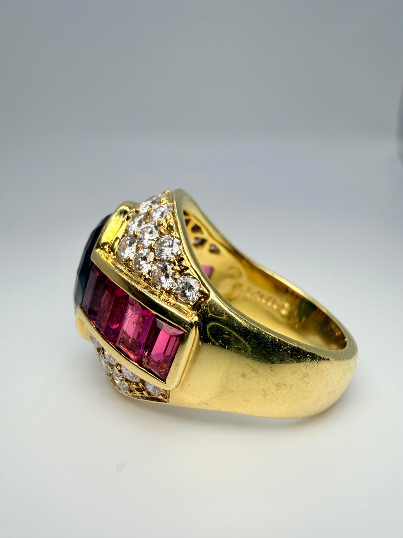 18K Yellow Gold Lagos Ring With Oval Green Tourmaline Center Stone 14X10 And 8 Pink Tourmaline Emerald Cut Side Stones 5X3Mm. There Are 32 Round Diamonds Approx .05Ct And 4 Diamonds Approx 0.10Ct Totalling Appro 2.00Ct
