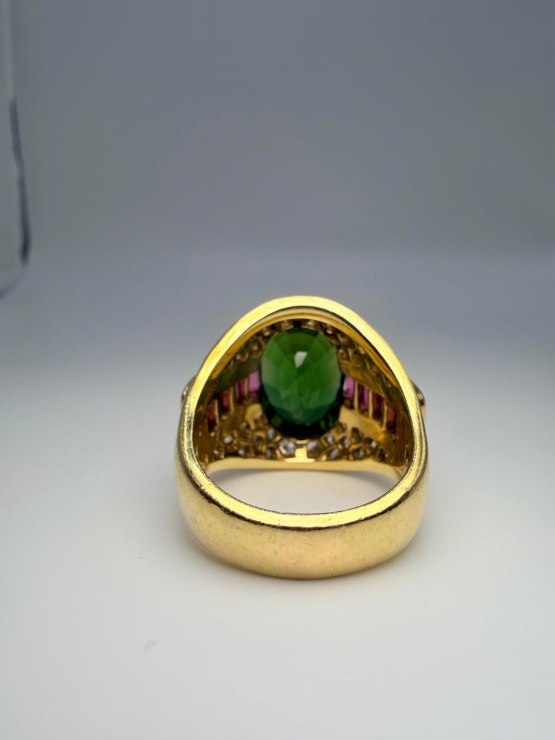 18K Yellow Gold Lagos Ring With Oval Green Tourmaline Center Stone 14X10 And 8 Pink Tourmaline Emerald Cut Side Stones 5X3Mm. There Are 32 Round Diamonds Approx .05Ct And 4 Diamonds Approx 0.10Ct Totalling Appro 2.00Ct