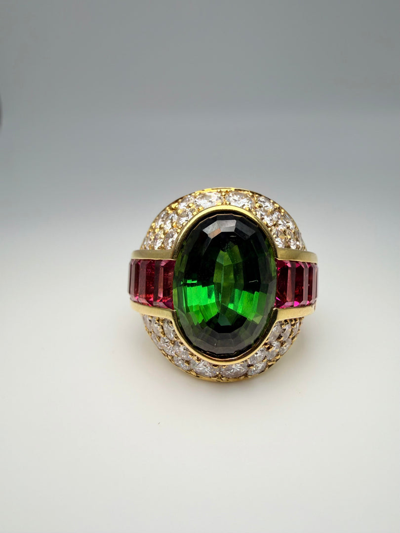 18K Yellow Gold Lagos Ring With Oval Green Tourmaline Center Stone 14X10 And 8 Pink Tourmaline Emerald Cut Side Stones 5X3Mm. There Are 32 Round Diamonds Approx .05Ct And 4 Diamonds Approx 0.10Ct Totalling Appro 2.00Ct